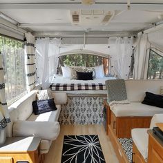 the inside of a camper with white curtains and black and white pillows on it