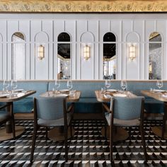 a restaurant with blue booths and checkered flooring in front of the windows, along with several empty wine glasses on the tables