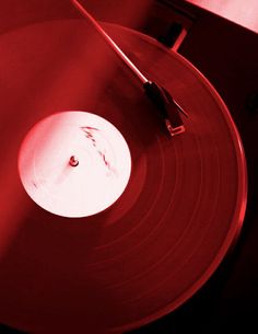 a turntable with red light coming from the top, and a record player's arm resting on it