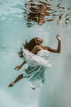 a woman floating in the water wearing a dress