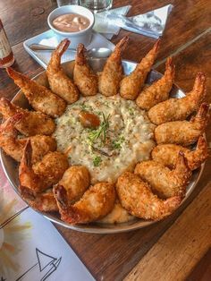 there is a large platter of fried shrimp on the table with dipping sauces