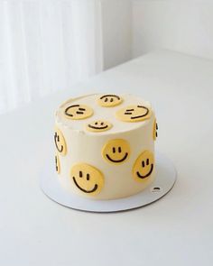 a white cake with yellow smiley faces on it