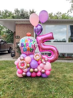 a large number five balloon with balloons in front of a house