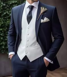 a man in a suit and tie standing next to a wall with plants on it