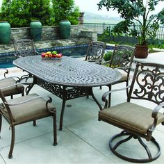 an outdoor table with chairs and fruit on it next to a swimming pool in the background