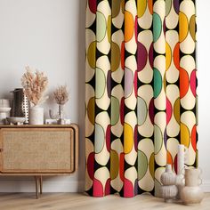 a colorful curtain with circles on it in front of a white wall and sideboard