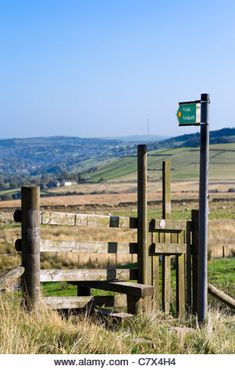 a wooden gate in the middle of a grassy field with hills in the back ground