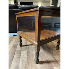 a wooden table sitting on top of a hard wood floor next to a black couch