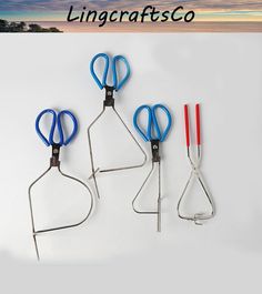 three scissors are hanging on the side of a white wall with an ocean in the background