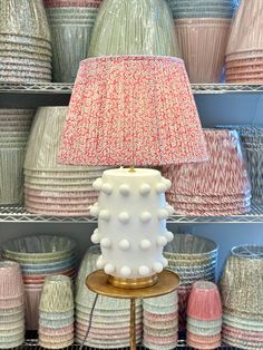 a table lamp sitting on top of a wooden stand in front of baskets filled with yarn