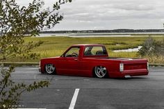 a red pick up truck parked in a parking lot next to a body of water