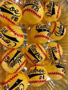 some yellow baseballs with black and red stitches on them are in a clear bowl