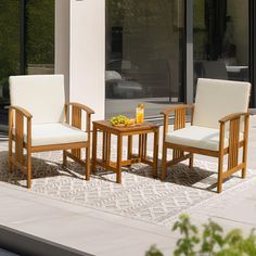 two chairs and a table with drinks on it in front of a glass doored building