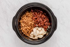 beans and other foods are in a crock pot on a marble counter top, ready to be cooked