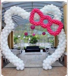 an arch decorated with balloons in the shape of a heart and pink bow on it