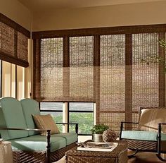 a living room filled with furniture and windows covered in bamboo blindes on top of them