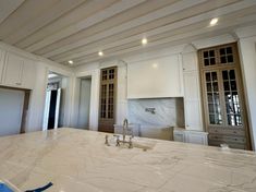 a large kitchen with marble counter tops and white cabinetry, along with an island in the middle