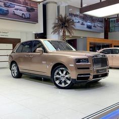 a tan rolls royce parked in a showroom