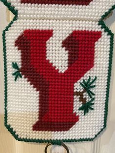 a cross - stitch letter y hanging on a door