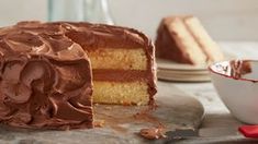 a cake with chocolate frosting sitting on top of a table next to a bowl