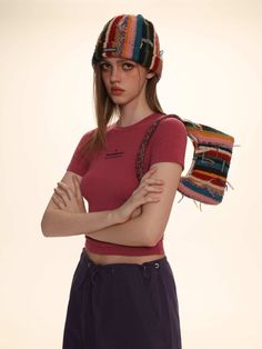 a young woman wearing a colorful hat and holding her arms crossed in front of her chest