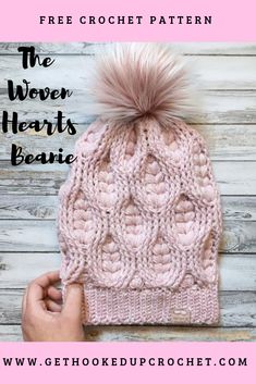 a pink knitted beanie with a pom - pom on top