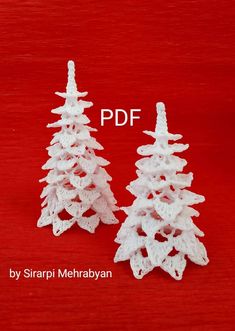 two crocheted christmas trees sitting next to each other on a red tablecloth