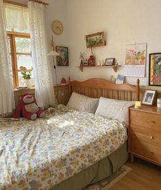 a bed room with a neatly made bed and wooden dressers next to a window