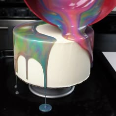 the cake is decorated with multicolored icing and has a spoon sticking out of it