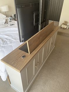 a bed room with a large tv on top of a wooden cabinet next to a bed