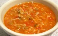 a white bowl filled with lots of soup on top of a tablecloth covered table