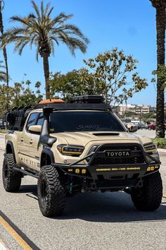 the toyota truck is driving down the street with palm trees in the backgroud