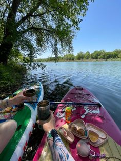 a person sitting in a kayak with food and drinks on the water's edge