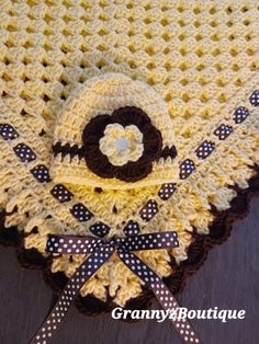 a crocheted yellow blanket with black and white polka dots on the edge, sitting on a wooden surface