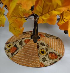 an orange and yellow umbrella sitting on top of a table next to some autumn leaves