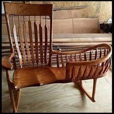 a wooden rocking chair sitting on top of a floor next to a pile of wood planks