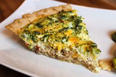 a slice of quiche with broccoli on a white plate