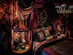 a bed with red and purple bedspread, chandelier, and pillows