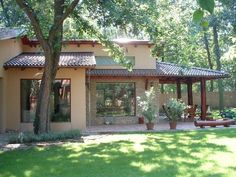 a house with lots of trees and plants in the front yard