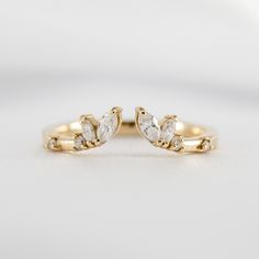 two gold wedding rings with white diamonds on the top and one diamond in the middle