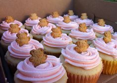 cupcakes with pink frosting and teddy bears on top are in a box