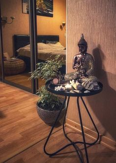 a small buddha statue sitting on top of a table next to a potted plant