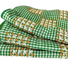 green and white checkered tablecloth with orange flowers on it, folded in three rows