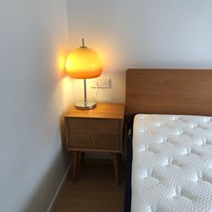 a bed with a night stand next to it and a lamp on the side table