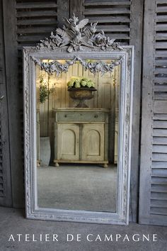 a large mirror sitting on the side of a wall next to a dresser and potted plant