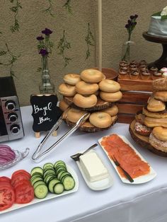 an assortment of food is displayed on a white tablecloth with flowers in the background