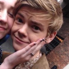 two young people are posing for a photo with their hands on each other's shoulders