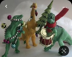 three toy dinosaurs with christmas hats and drums