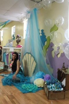 a woman is sitting on the floor in front of balloons and other items at a party