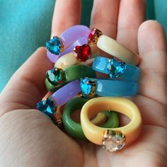 a person is holding several rings in their hand with different colored stones on them,